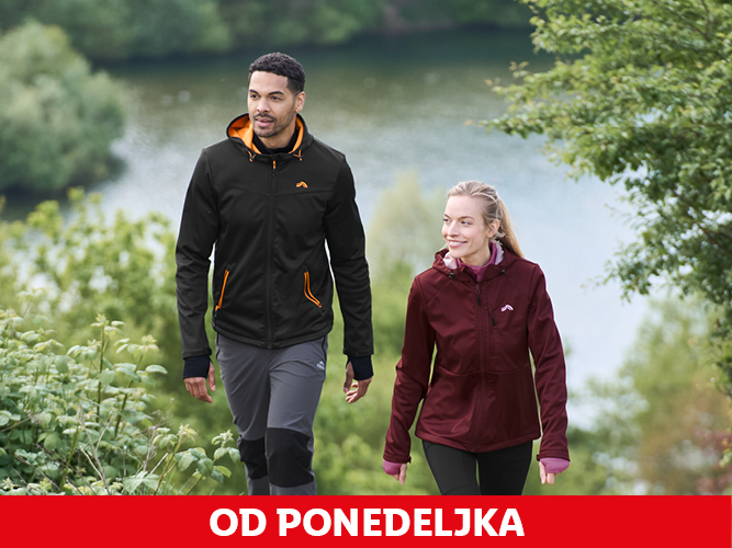 Moški in ženska v pohodniških jaknah in hlačah ob jezeru.