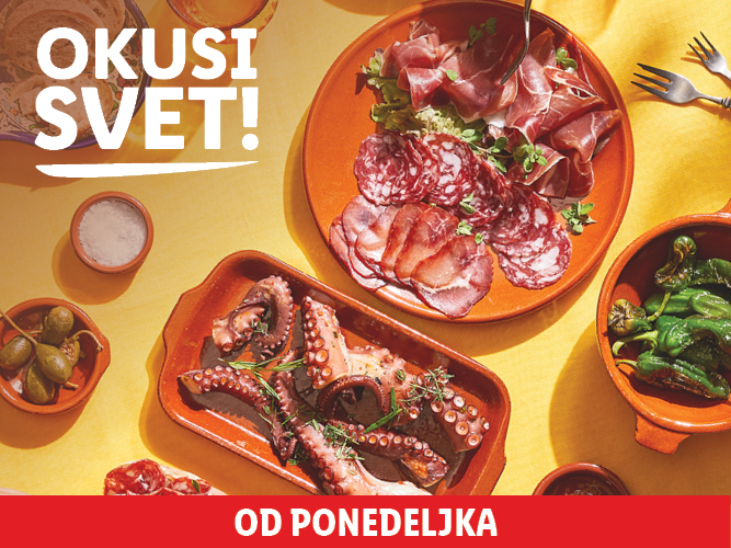 Pladenj s suhomesnatimi izdelki, hobotnica in paprika na rumeni mizi.