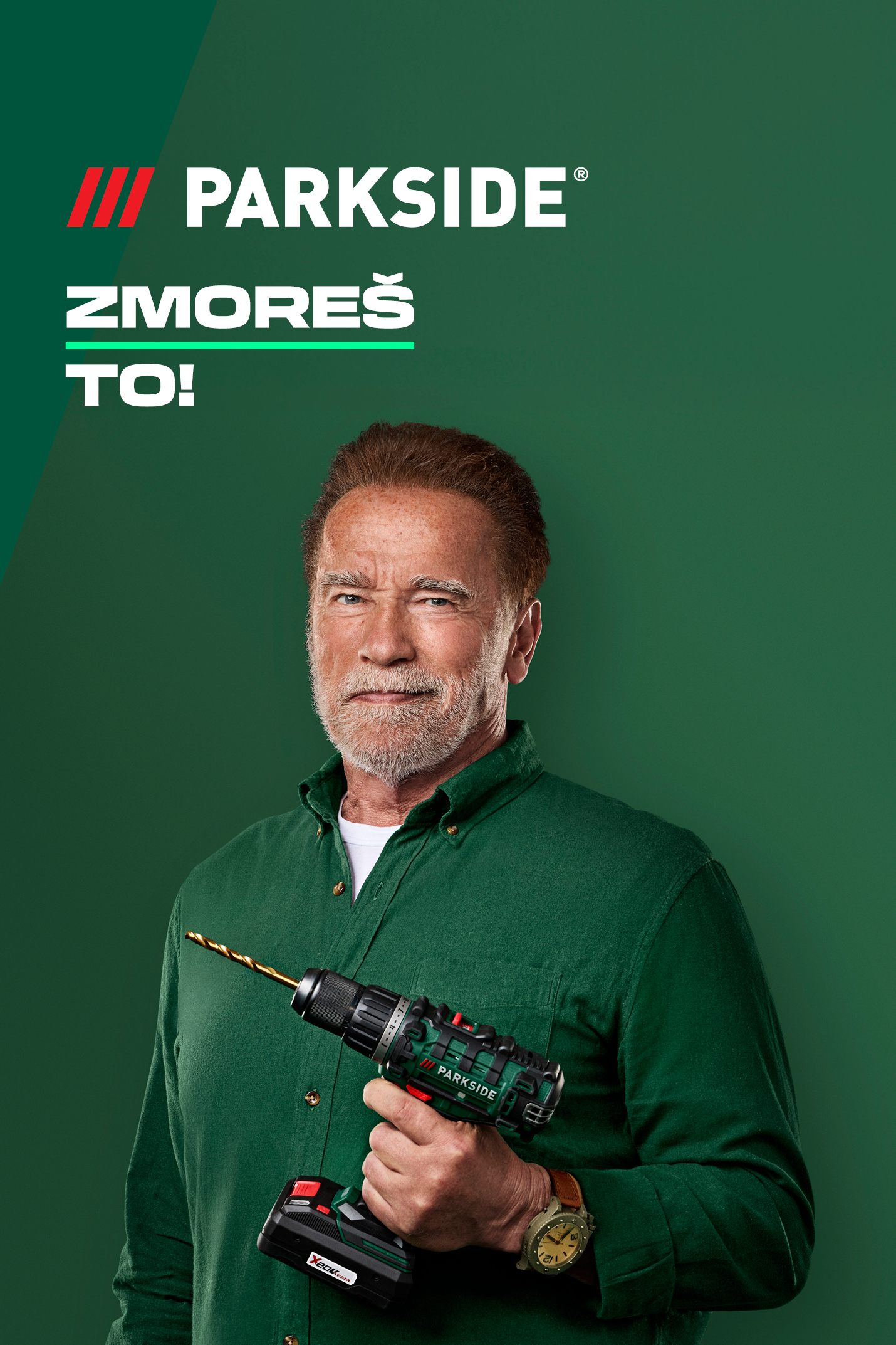 Arnold Schwarzenegger drži vrtalnik na zeleni podlagi.