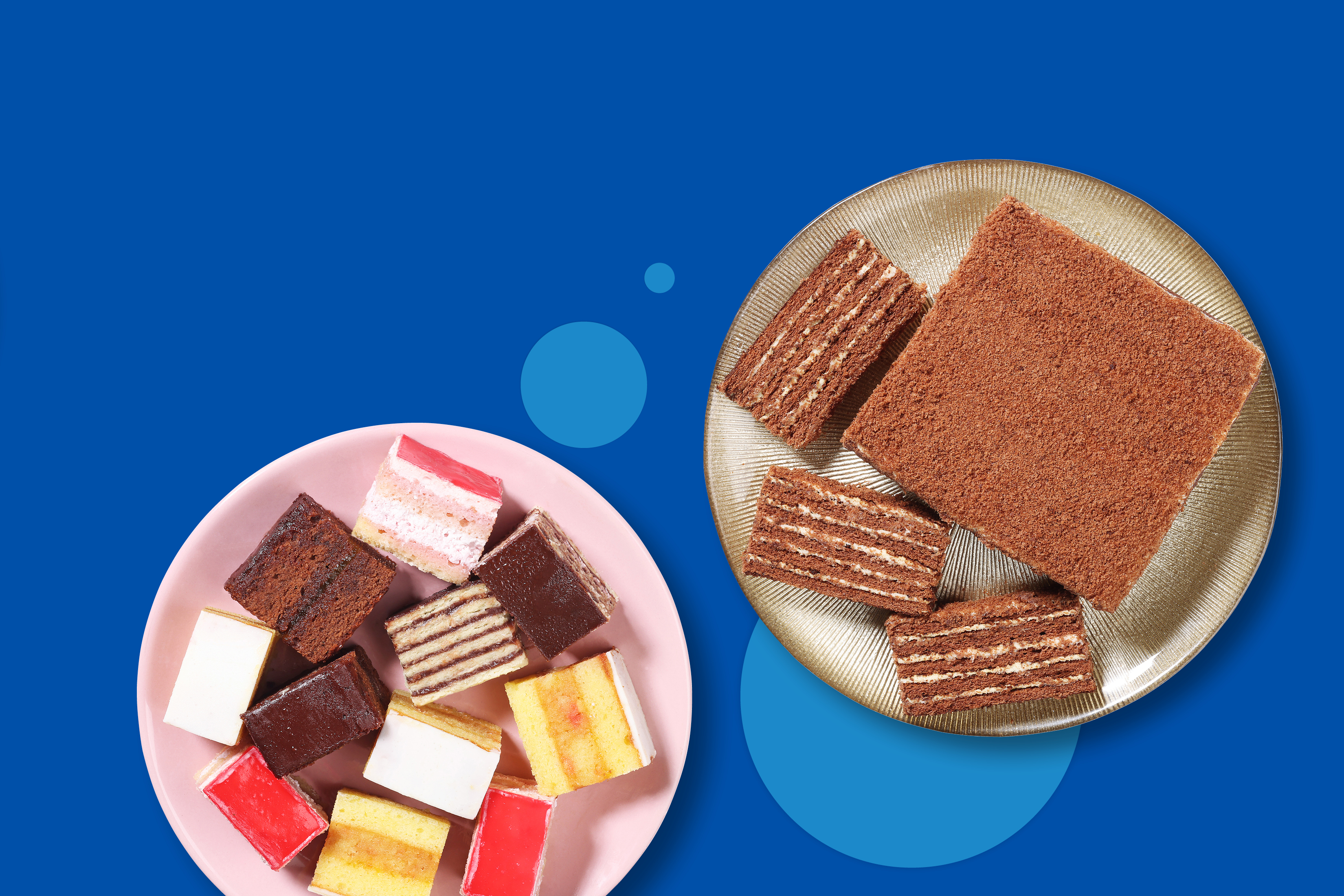 Različne vrste kolačkov in čokoladna torta na modrem ozadju.