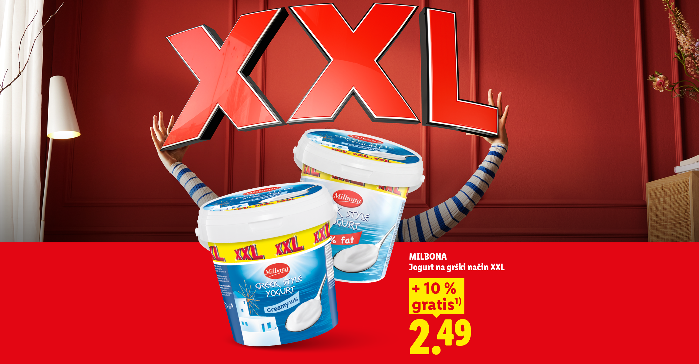 Ženska drži velike rdeče črke XXL, poleg pa sta dva velika grška jogurta z 10 % gratis in ceno 2,49.