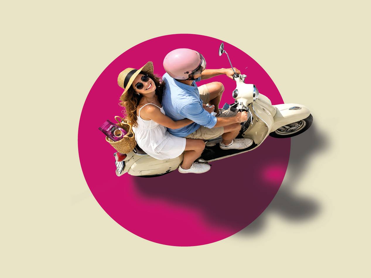 Par na skuterju z vrečko kave v košari, obkrožen z rožnatim krogom.