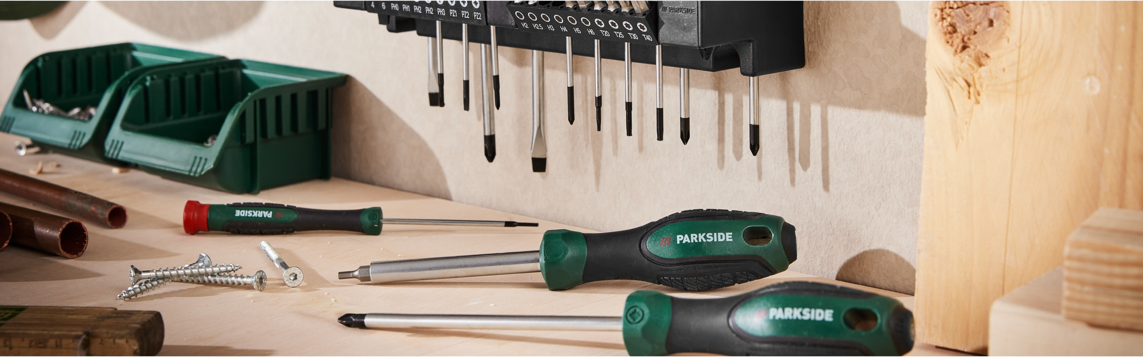 Komplet izvijačev in nastavkov Parkside, razporejen na steni in mizi.