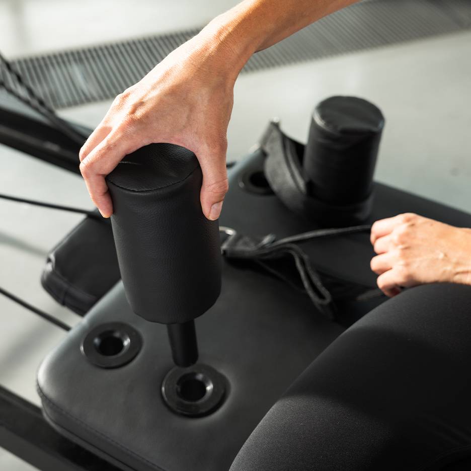 Oseba nastavlja črno oblazinjeno vadbeno napravo.