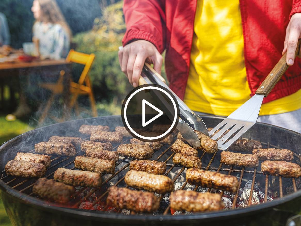 Oseba peče čevapčiče na žaru na vrtu.
