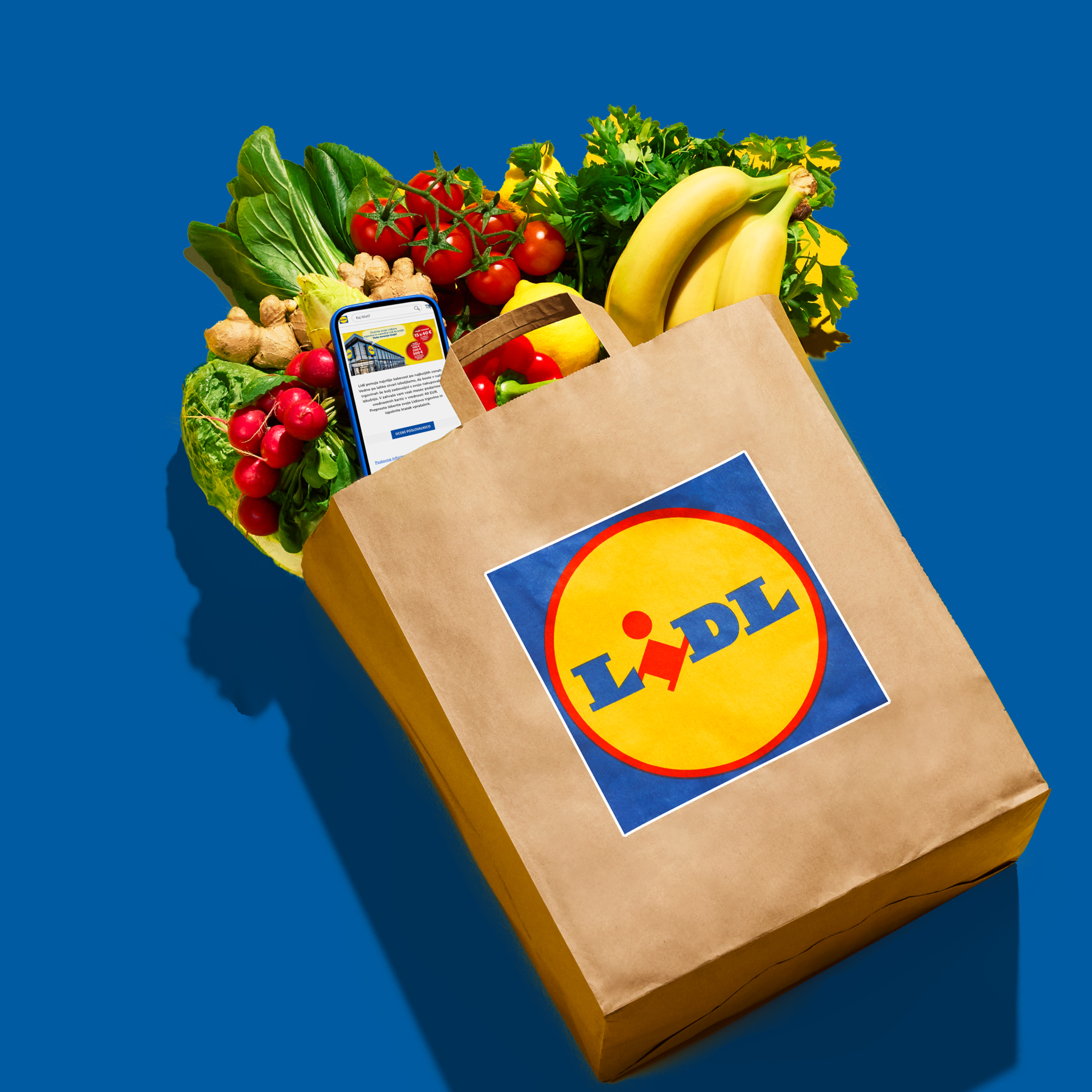 Nakupovalna vrečka s svežo zelenjavo, sadjem in telefonom z aplikacijo.