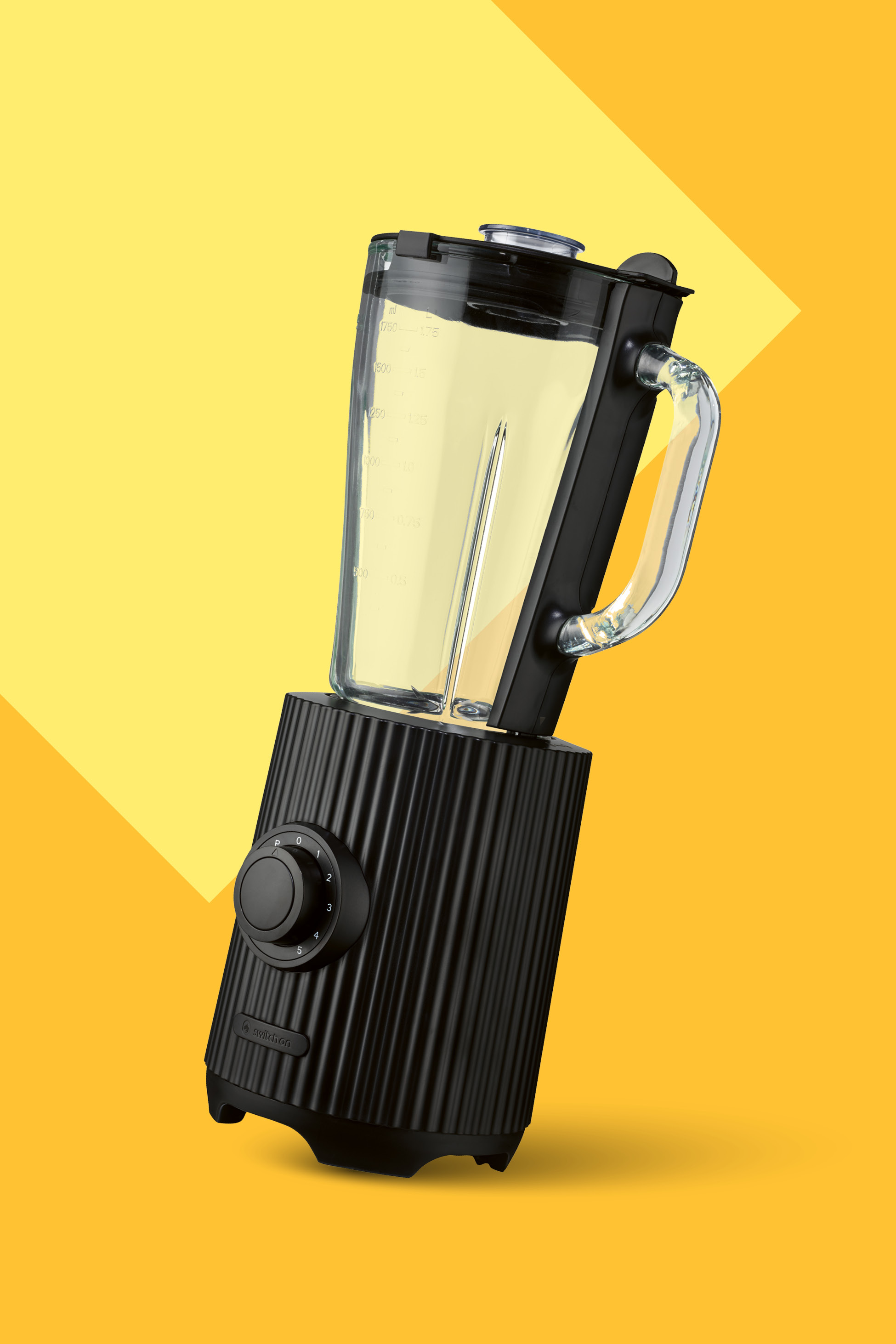 Črn mešalnik s prozorno posodo, napolnjeno z rumeno tekočino, na rumenem ozadju.