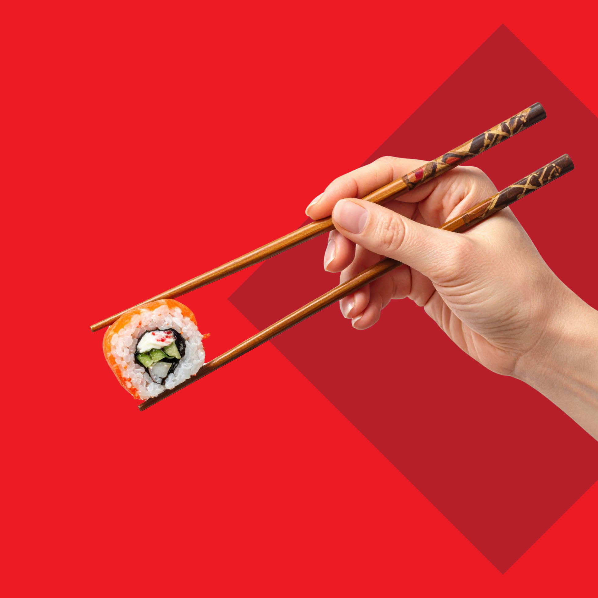 Roka drži suši z bambusovimi palčkami na rdečem ozadju.