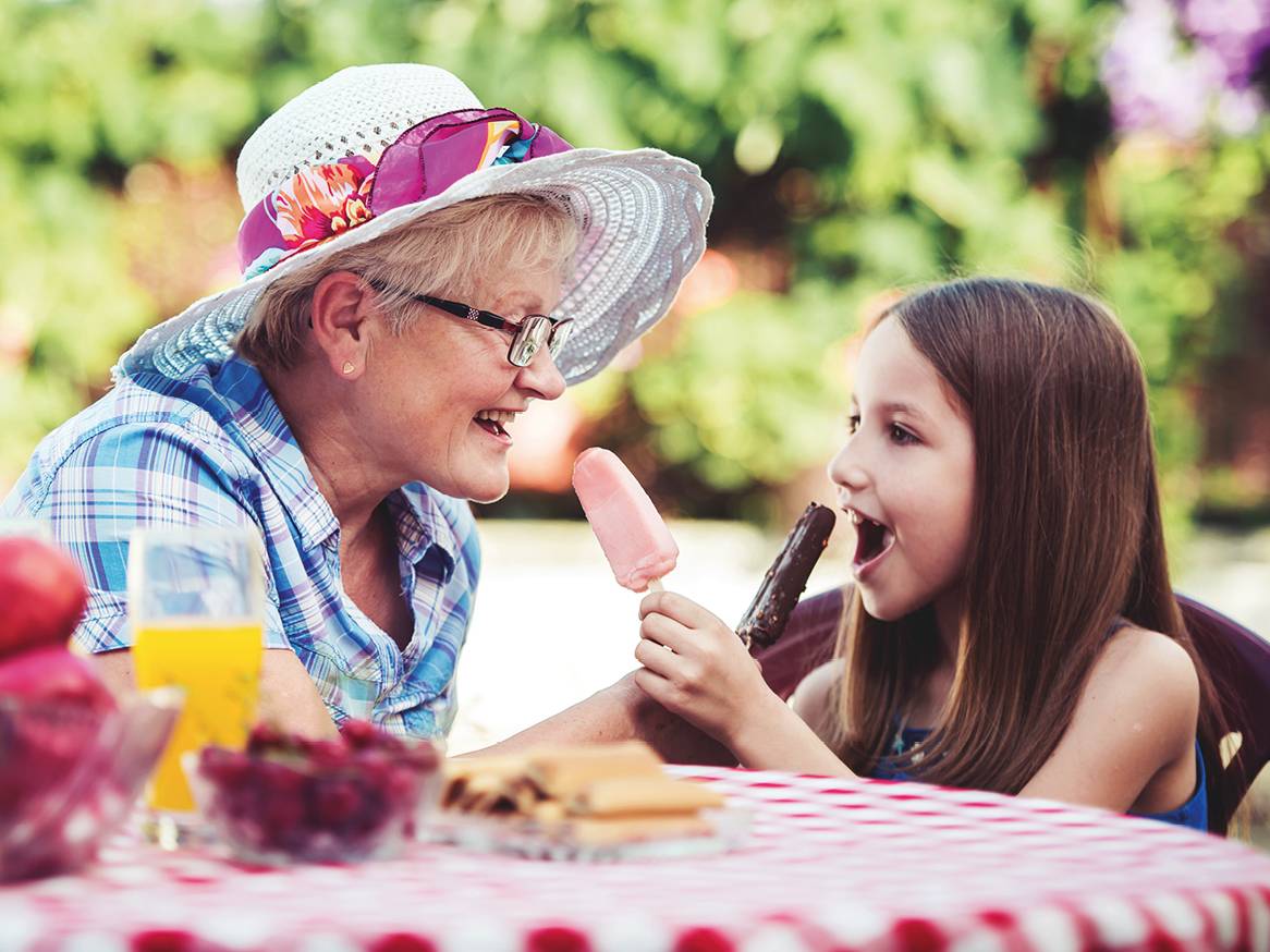 Babica in vnukinja uživata v sladoledu na palčki in sadju na pikniku.