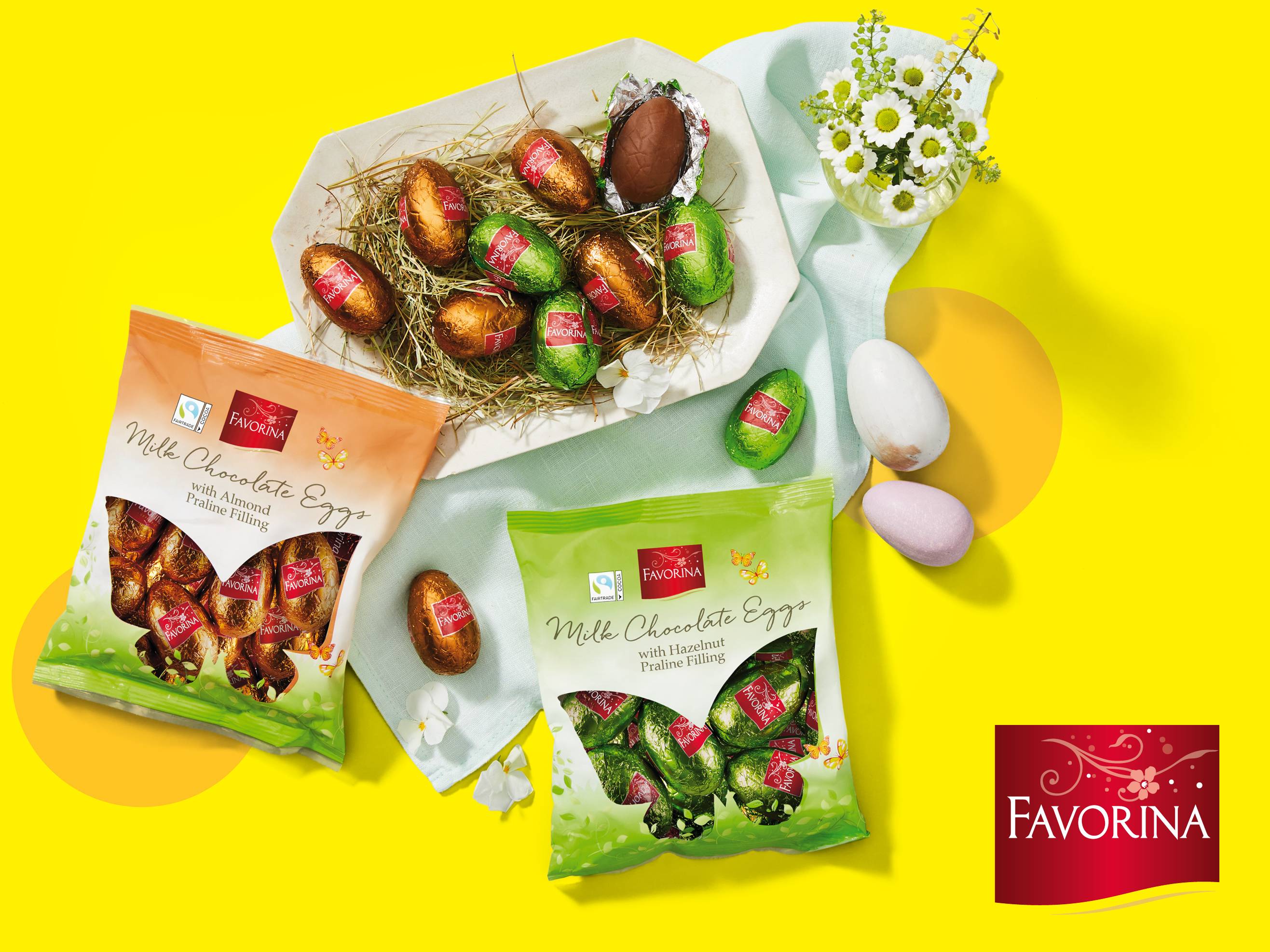 Velikonočna jajca iz mlečne čokolade z mandljevim in lešnikovim pralinejem v embalaži in na pladnju.