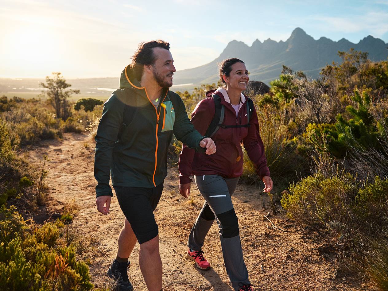 Par v pohodniških oblačilih in nahrbtnikih hodi po gorski poti.