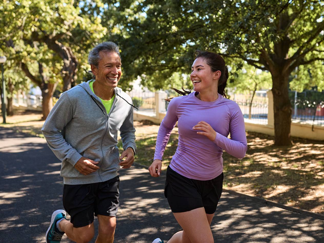 Moški in ženska tečeta v športnih oblačilih po parku.