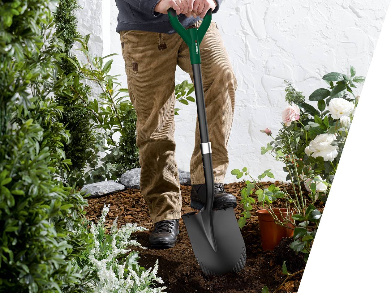 Oseba koplje z lopato Parkside v vrtu z grmovjem in vrtnicami.