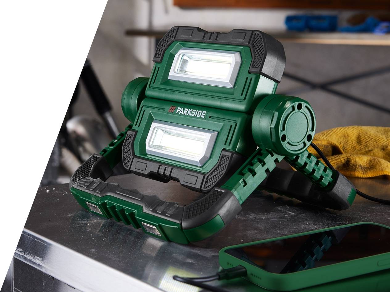 Zelena delovna svetilka Parkside na mizi, poleg nje je telefon.