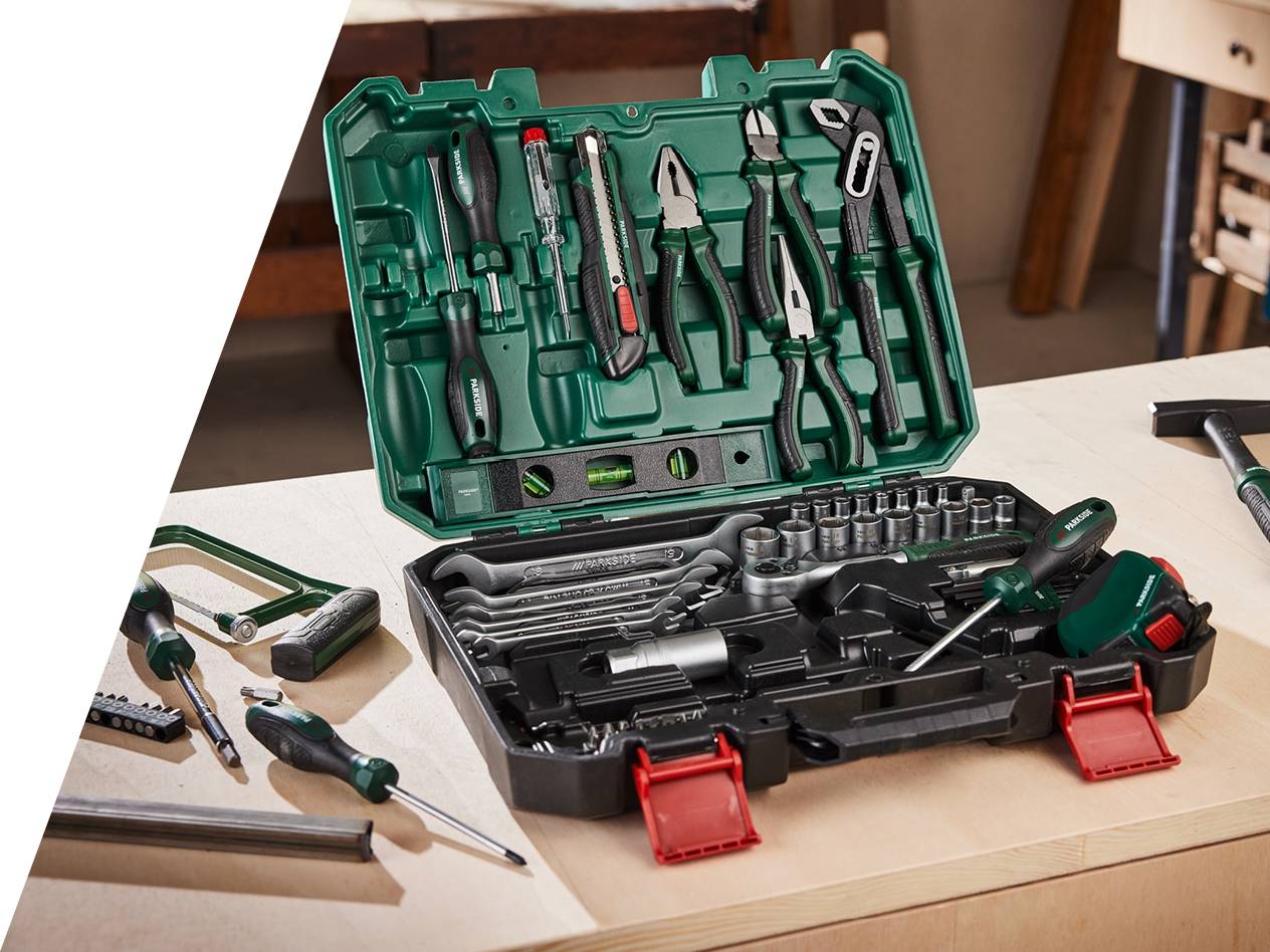 Odprt komplet orodja Parkside z izvijači, kleščami, ključi in kladivom na leseni mizi.