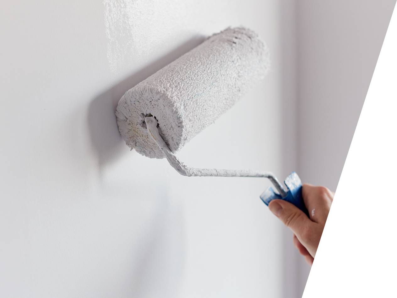 Roka drži valjček za barvanje in barva steno v belo barvo.