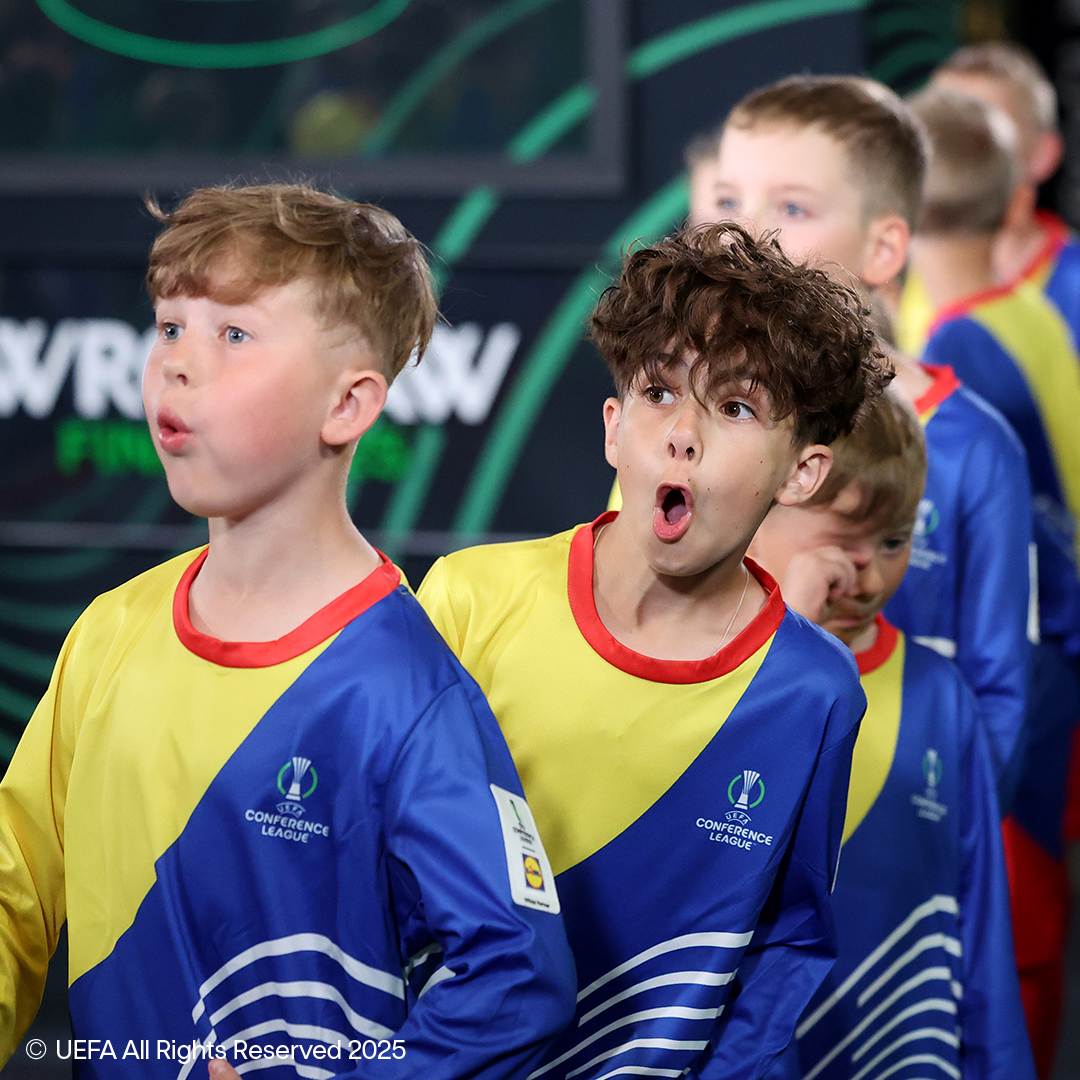 Dva fanta v rumenih in modrih nogometnih dresih z logotipi UEFA Konferenčne lige.