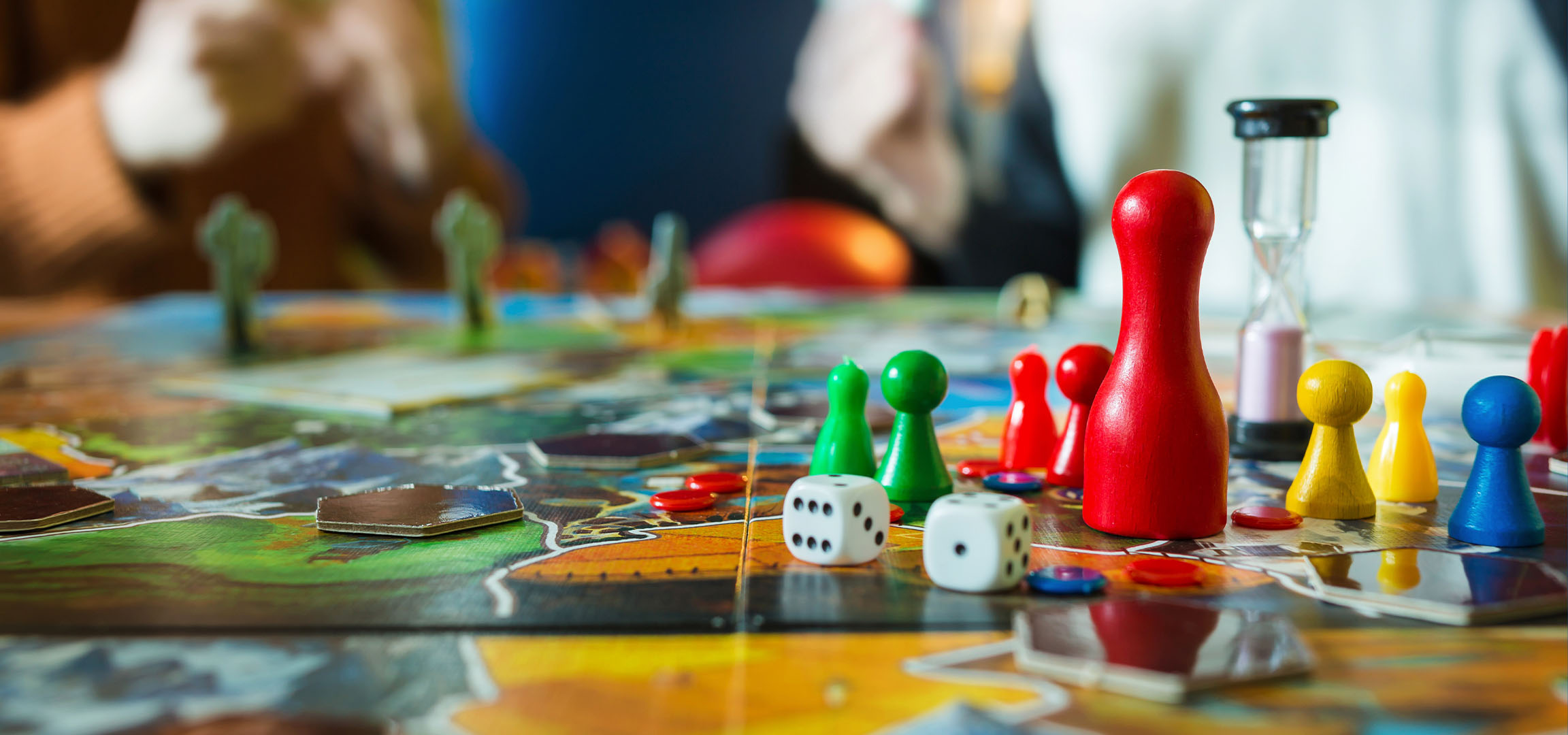 Barvne figure družabne igre, vključno z rdečimi, zelenimi, rumenimi in modrimi kmeti, s kockami.