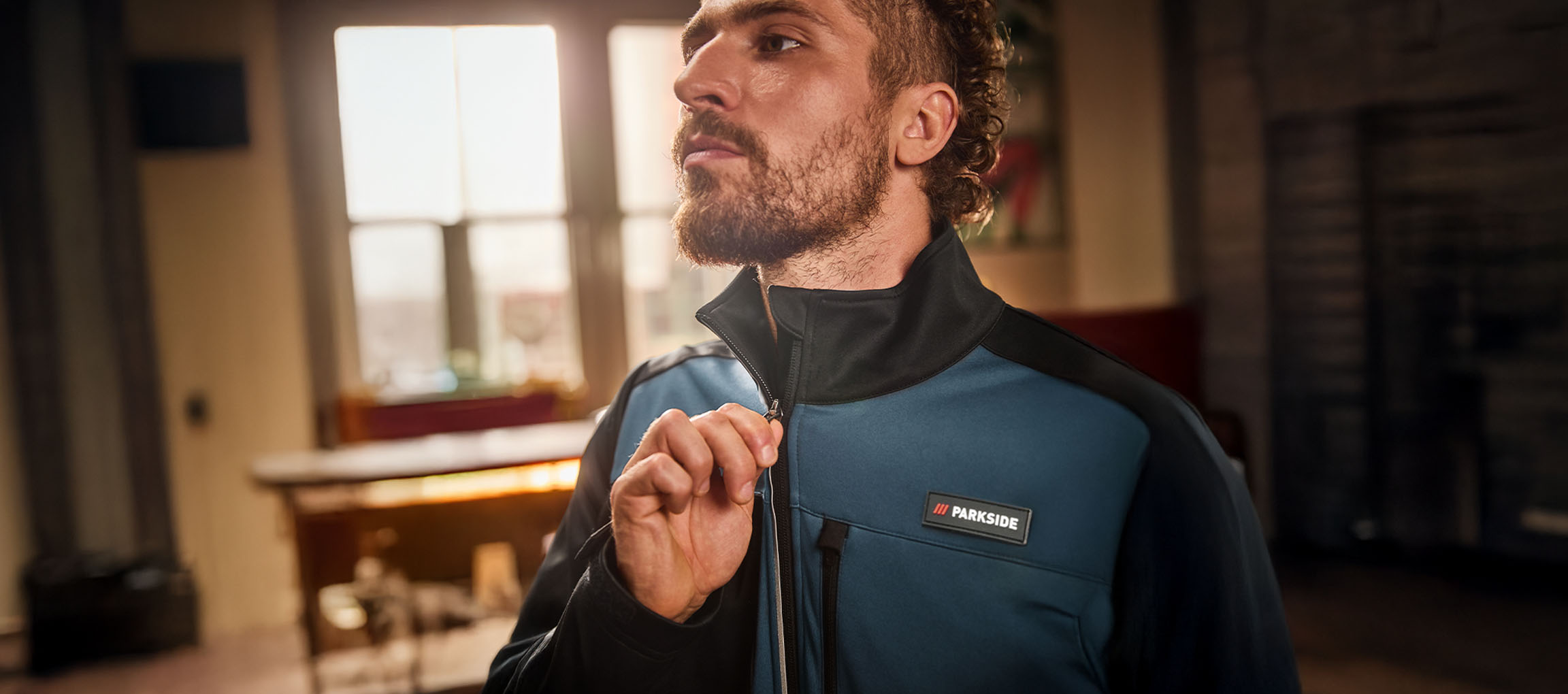 Moški v modro-črni delovni jakni Parkside si jo zapenja