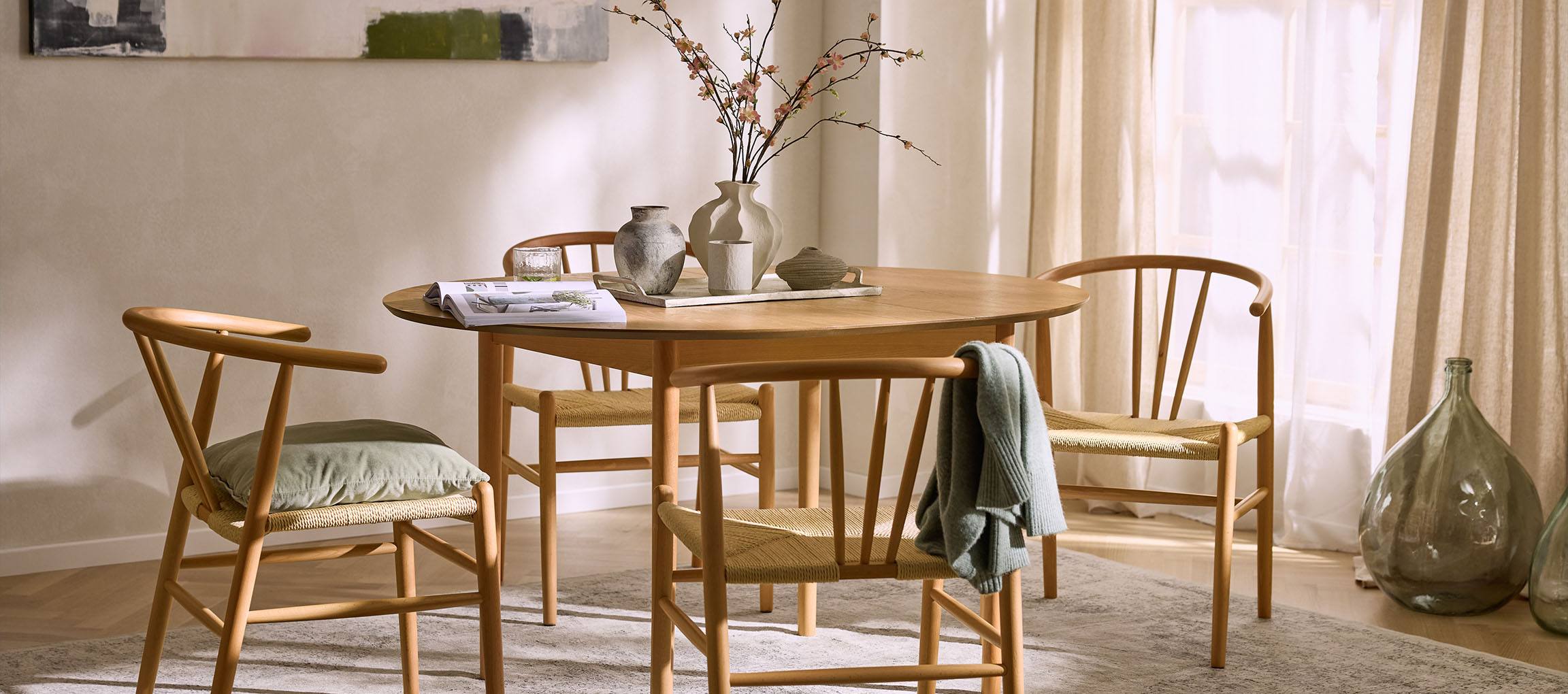 Jedilnica z okroglo leseno mizo, lesenimi stoli z vrvnimi sedeži in okrasnimi vazami.