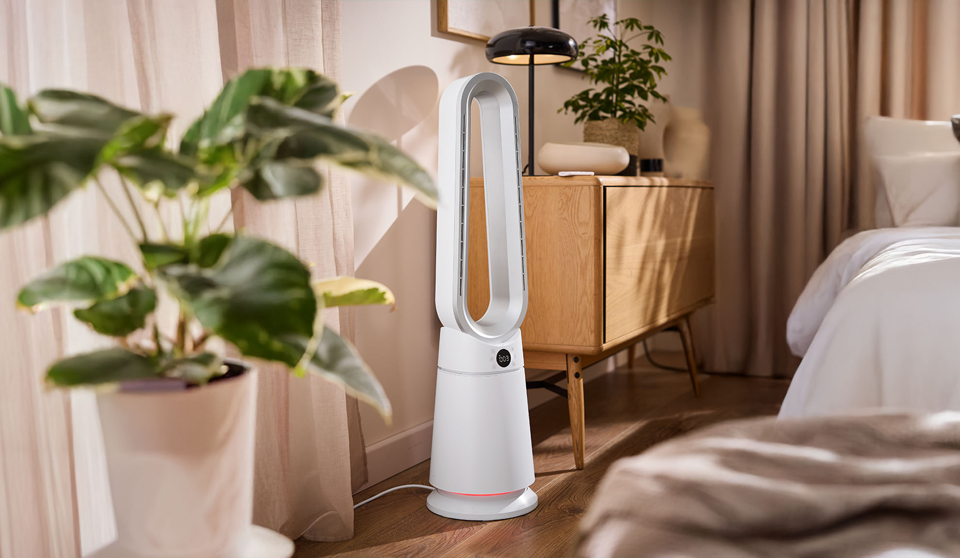 Beli stolpni ventilator v moderni spalnici z rastlinami in lesenim pohištvom.