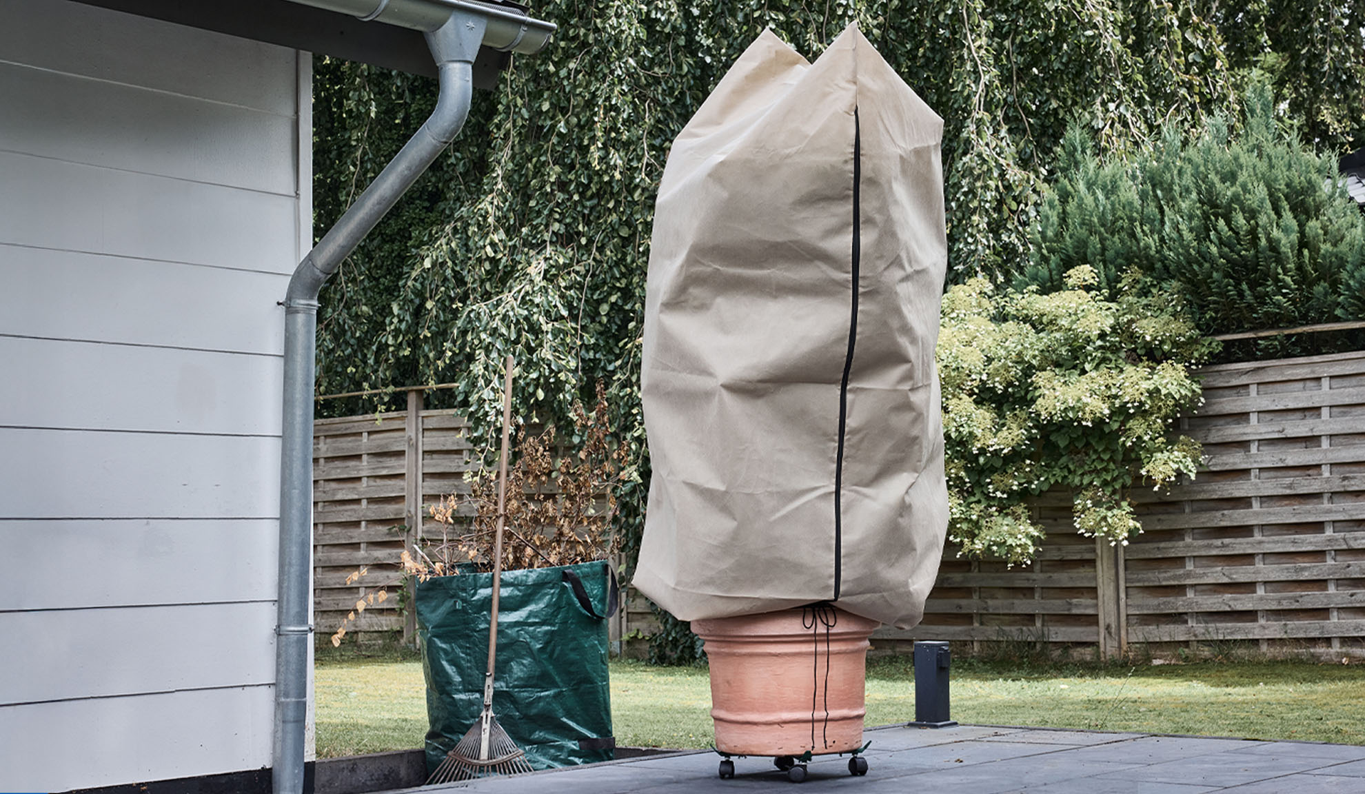 Prekrivalo za rastline v loncu na terasi z žlebom in grabljami.