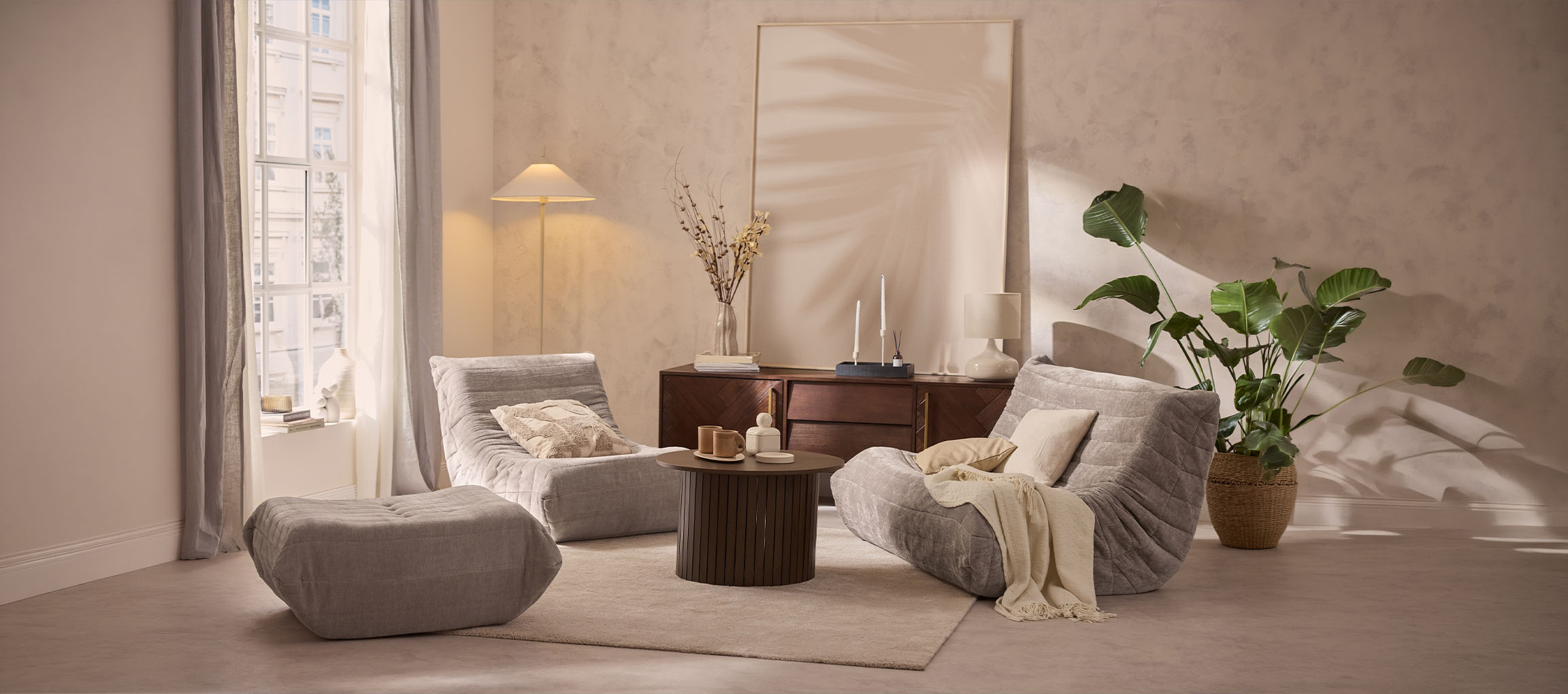 Udobna dnevna soba z dvema sivima ležalnikoma, otomanom in leseno mizo.