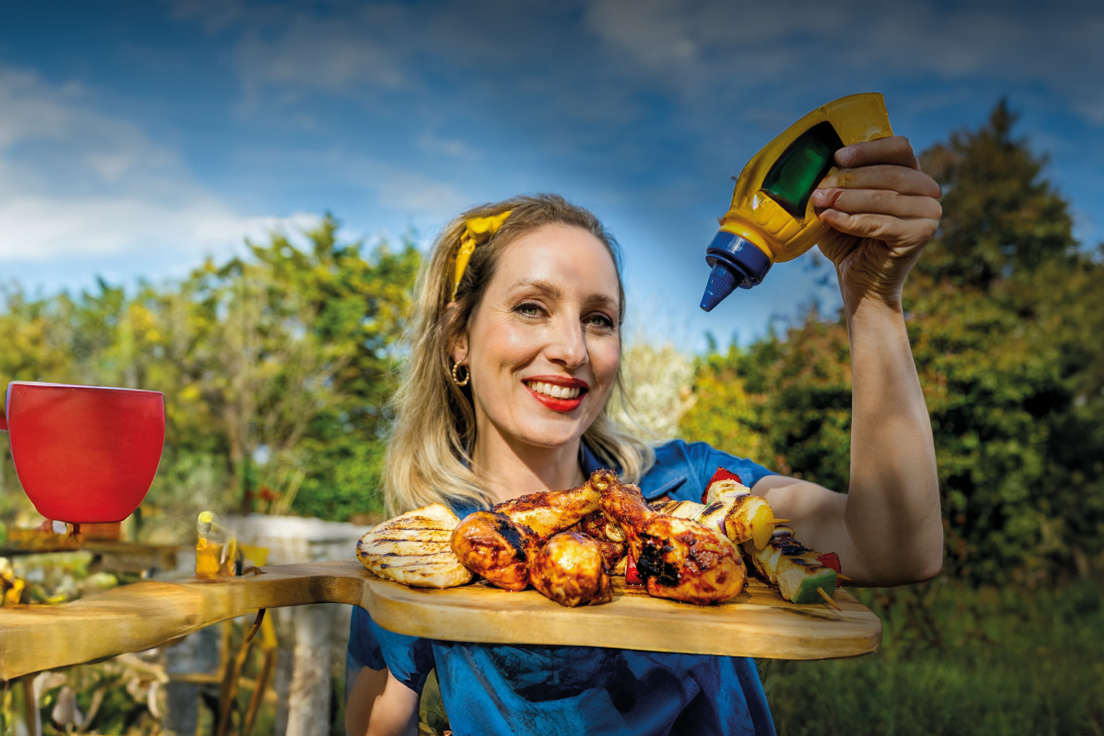 Ženska drži pladenj z žarom in stiska steklenico gorčice.