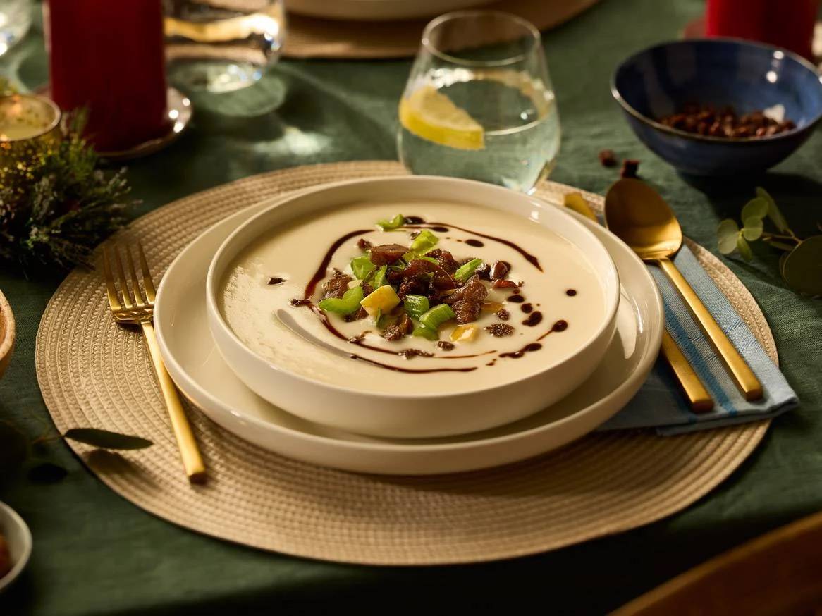 Kremna juha z zelenjavo in balzamičnim prelivom na praznični mizi.