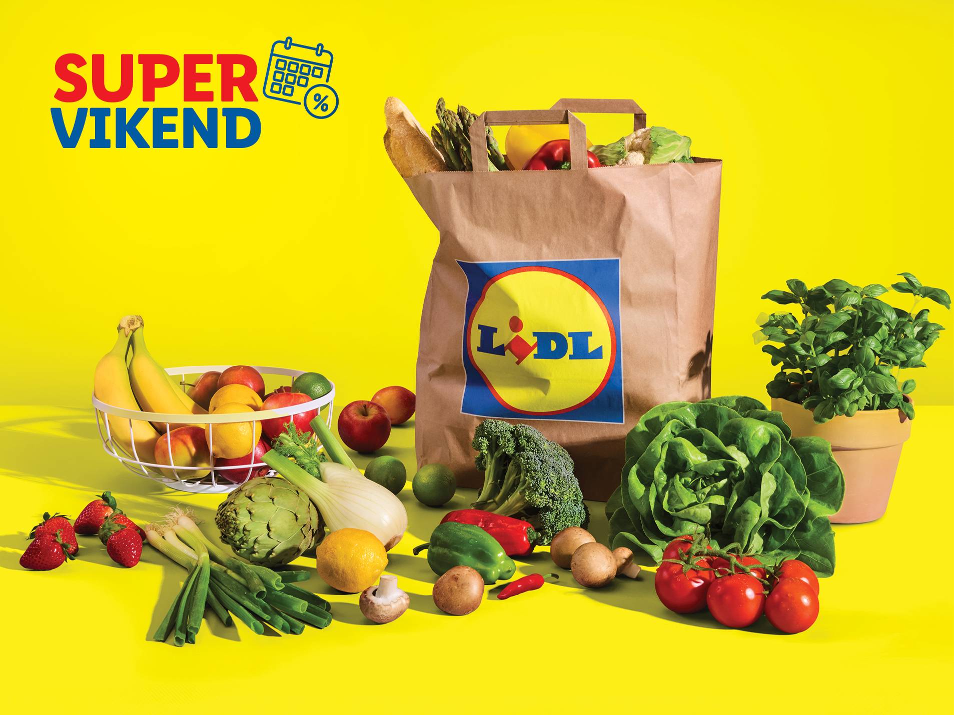 Lidl-ova nakupovalna torba, polna sveže zelenjave in sadja, na rumenem ozadju, s promocijskim napisom Super Vikend.